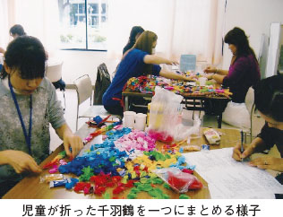 児童が折った千羽鶴を一つにまとめる様子。折り紙の千羽鶴をまとめるボランティア人々