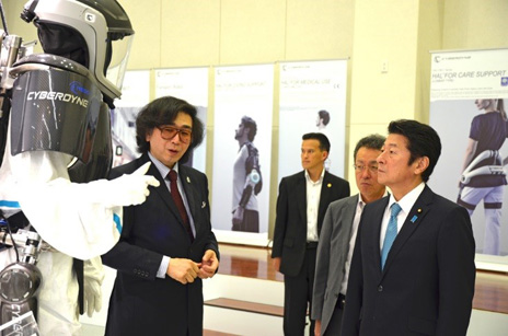 ＩｍＰＡＣＴ山海ＰＭ（サイバーダイン社ＣＥＯ）より災害対策用ロボットの説明を受ける松山大臣