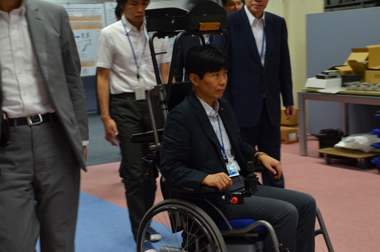 自律移動車いすに試乗する山本大臣　写真