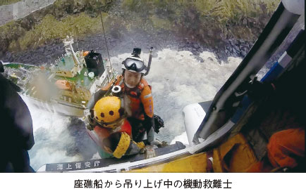 座礁船から吊り上げ中の機動救難士。座礁船の船員を救助している機動救難士の写真