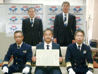 海上保安庁の職員と日本ライフセービング協会の職員が並んでいる様子。中央の1人は感謝状を持っている