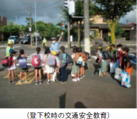 （登下校時の交通安全教育）。交差点に児童が集まって警察官の指導を受けている