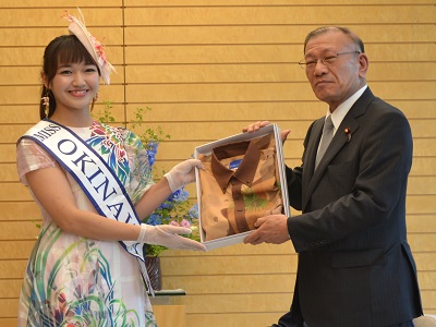 ミス沖縄のスピーナ瑛利香さんからかりゆしウェアを贈呈される宮腰大臣